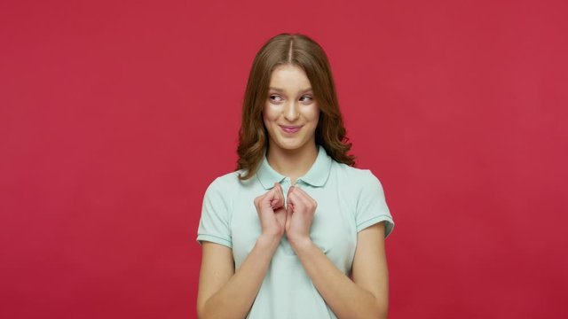 Beautiful cunning young woman in polo t-shirt having tricky plan in mind, thinking over cheats, devious revenge, gesticulating and pondering sly prank. indoor studio shot isolated on red background