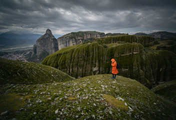 Tourist standing Meteora rocks, girl on orange jacket on Meteora Rocks, Greece