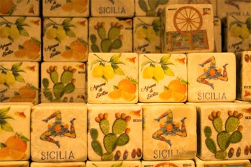 colored images reproduced on cube-shaped stones promoting the Sicily region in Italy 
depicting citrus fruits, lemons, oranges, cactuses typical Sicilian cart and 
female head with three folded legs c
