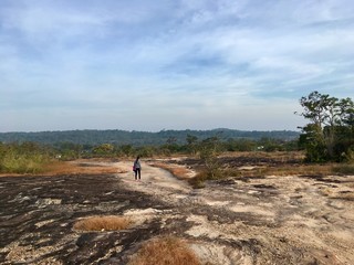 The girl walking on gravel road in forest, difficult way more tree sideways and blue sky background