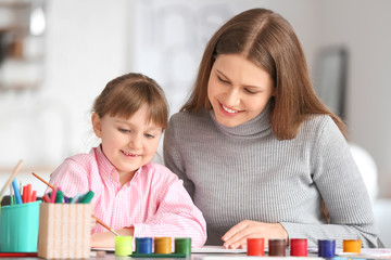 Fototapeta premium Drawing teacher giving private art lessons to little girl at home
