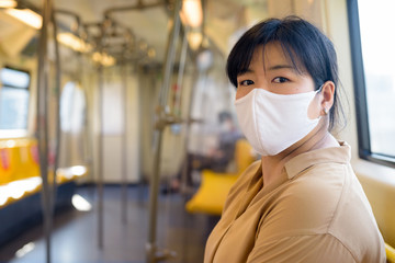 Fototapeta na wymiar Overweight Asian woman with mask sitting with distance inside the train