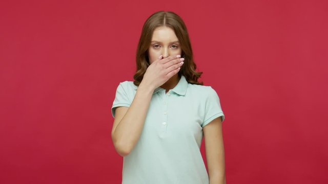 I will not say anything to anyone. Scared intimidated young woman in polo t-shirt covering her mouth to keep secret, afraid to talk, confused and terrified with terrible truth. studio shot isolated
