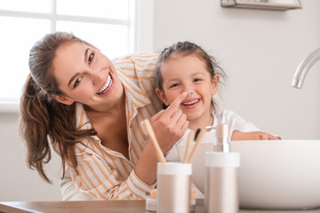 Little daughter with her mother washing hands in bathroom
