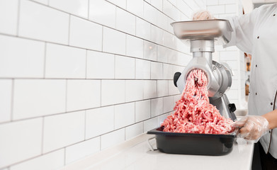 Incognito female butcher doing minced meat.