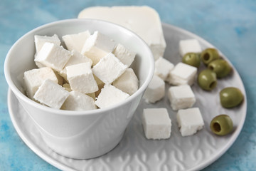 Plate with tasty cut feta cheese and olives on table
