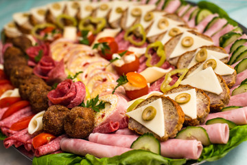 Plate of arranged, delicious cold cuts with mozzarella, tomato, olive, rolled ham, salami and cheese. Selective focus