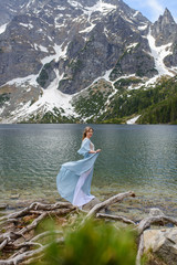 Portrait of a young woman on the background of the Polish lake "Sea Eye" in the Tatra Mountains. Portrait photography in the background of a quiet place without people.