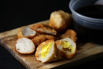 Delicious pempek palembang and cuko sauce on a wooden board. Indonesian traditional fish cakes, perfect for food blogs & menus.