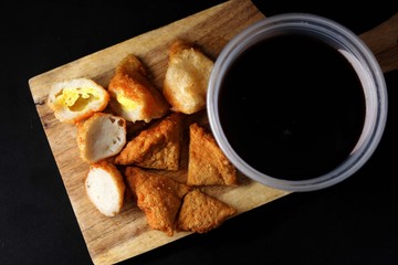 Delicious pempek palembang and cuko sauce on a wooden board. Indonesian traditional fish cakes, perfect for food blogs & menus.