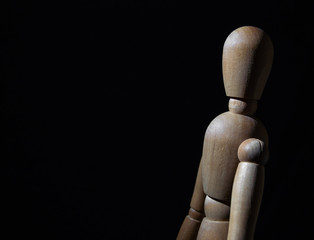 a wooden toy stands on a black background
