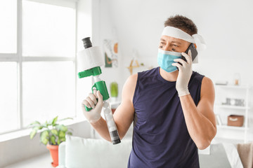 Funny man with toy gun and toilet paper talking by mobile phone at home. Concept of coronavirus epidemic