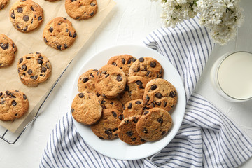 Composition with chip cookies, flowers and milk on white table, top view