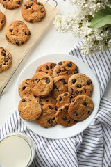 Composition with chip cookies, flowers and milk on white table, top view