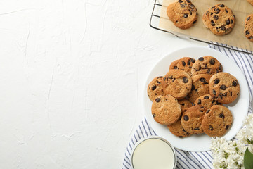 Composition with chip cookies, flowers and milk on white table, top view