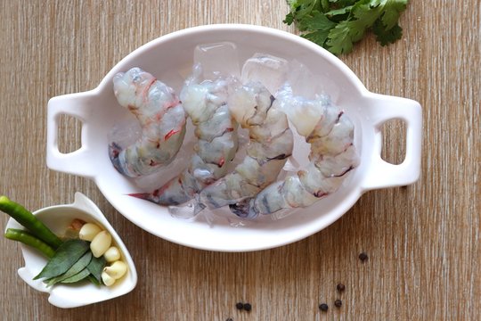 Cleaned, Peeled & Deveined Tiger Prawns or Asian tiger Shrimps. Also known as Kolambi or Bagda chingri. Recipe ingredients like pepper, chilies, garlic, curry leaves at background with copy space. 