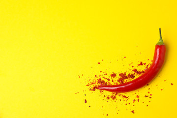 Tasty chilli pepper and powder spice on yellow background