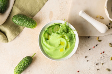 Bowl with cold cucumber soup on light background