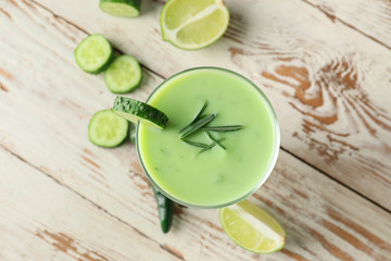 Glass with cold cucumber soup on table