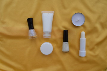 Set of cosmetics for makeup and manicure, candle on a yellow background. The view from the top.