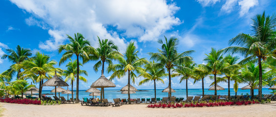 Public beach with lounge chairs and umbrellas in Pointe aux Canonniers, Mauritius island, Africa