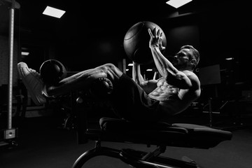 Monochrome portrait of man training abs with ball.