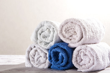 Obraz na płótnie Canvas White and dark blue towels for bath rolled up