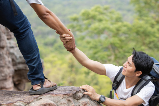 A man helping his friend By pulling hands up on the cliff