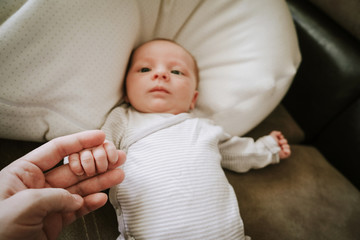 New family. Mom with son. Newborn child holding mother's hand. Selective focus on fingers.