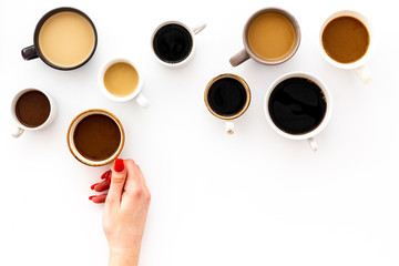 Coffee addiction. Mug in hand, many cups on white background top view copy space