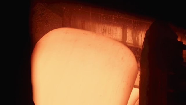 The red-hot sheet of metal rotates on the conveyor. Slow motions.