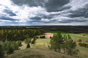 Krajobraz Suwalskiego Parku Narodowego. Widok z Cisowej Góry na lasy, łąki, pola, pagórki w pochmurny dzień