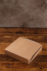 Big brown paper box isolated on wooden background. Eco-friendly disposable food packaging. Preserving nature and recycling concept.Copy space.
