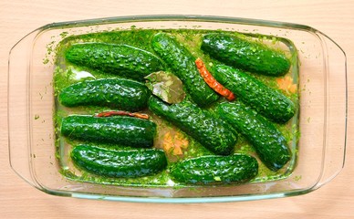 Freshly pickled cucumbers in a glass container. Ingredients- cucumbers, water, bay leaf, red...