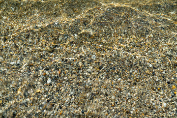 Sea texture of transparent water and pebbles