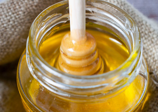 selective focus. Honey stick with honey is removed from a jar of honey. window background.