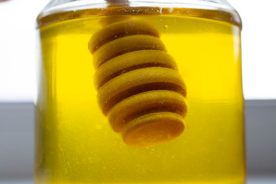 soft focus. Honey stick inside a jar of honey. against the backdrop of the bright sun.