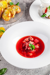 Modern Ukrainian cuisine in European style. Borsch soup with meat and sour cream. Beautiful serving dish in a restaurant in a white plate. background image, copy space text