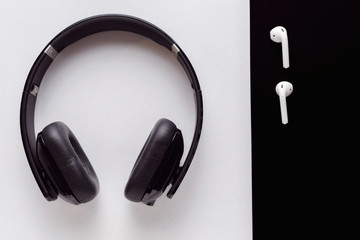 large black headphones on a white background, small white headphones on a black background top view with copy space for text