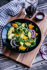 Salade verte avec des tranches d'avocat et d'orange  dans une assiette noire - Alimentation fraiche et saine