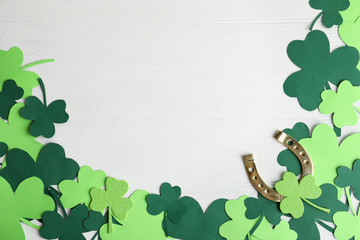 Flat lay composition with clover leaves and horseshoe on white wooden background, space for text....
