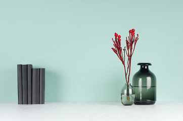 Spring soft students workplace with row black books and red decorative bouquet, glass vases in soft light white wood table and green mint menthe wall, copy space. - obrazy, fototapety, plakaty