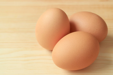 Three of Chicken Eggs Isolated on Wooden Table with Copy Space