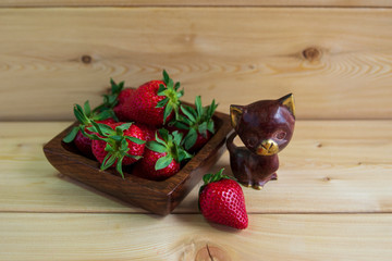 Red strawberries in a glass vase on a wooden background. No one. Good morning.