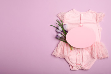 Child's clothes, flowers and card with space for text on pink background, flat lay