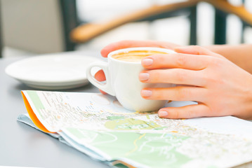 Woman study map drinking coffee in a street cafe. Redhead happy girl travel Canary islands and looking for a new place to visit. Sunny day.