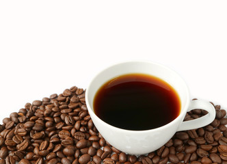 Cup of black coffee on the pile of roasted coffee beans isolated on white background