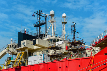Ship repair in shipyard with radio, radar mast and communication on navigation bridge deck during maintenance.
