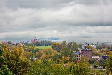 autumn landscape with houses and mountains on the horizon under a cloudy sky