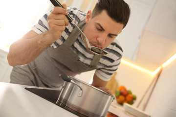Handsome man cooking on stove in kitchen